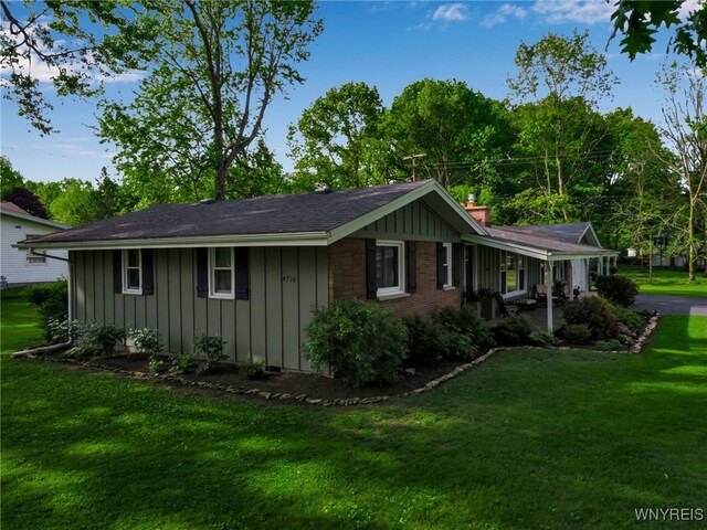 4710 Boncrest Dr E, Clarence, NY 14221 - view of home's exterior featuring board and batten siding, a lawn, and a chimney