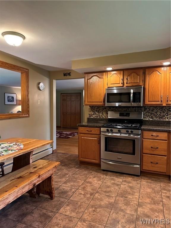 4710 Boncrest Dr E, Clarence, NY 14221 - kitchen with appliances with stainless steel finishes, dark countertops, tasteful backsplash, and brown cabinetry
