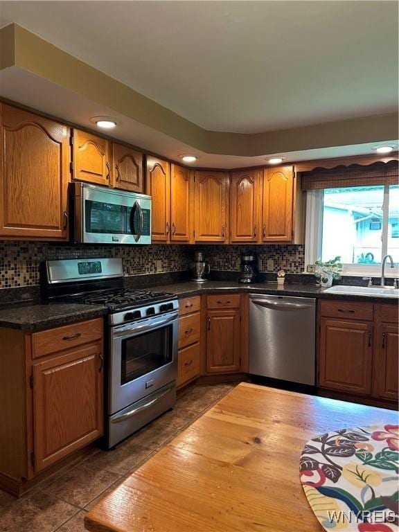 4710 Boncrest Dr E, Clarence, NY 14221 - kitchen featuring appliances with stainless steel finishes, a sink, brown cabinetry, tasteful backsplash, and recessed lighting