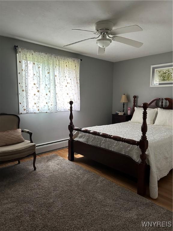 4710 Boncrest Dr E, Clarence, NY 14221 - bedroom featuring a baseboard heating unit, wood finished floors, and a ceiling fan