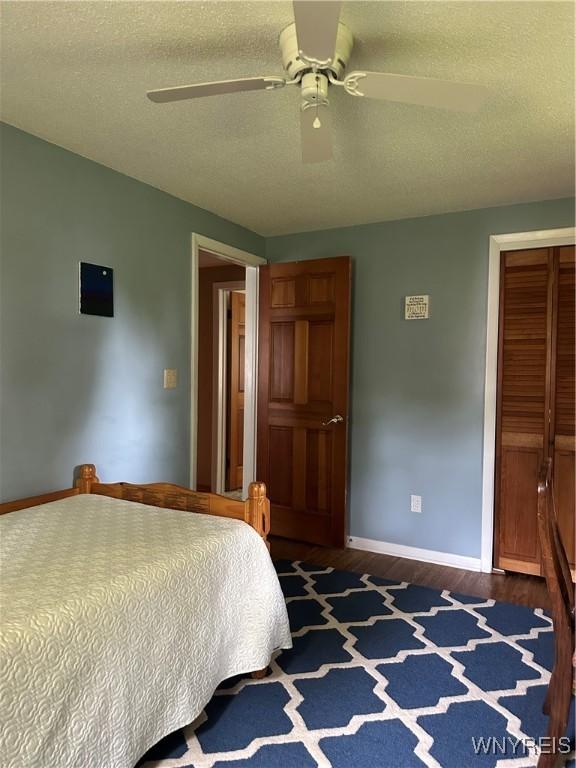 4710 Boncrest Dr E, Clarence, NY 14221 - bedroom with baseboards, dark wood-style flooring, a closet, ceiling fan, and a textured ceiling
