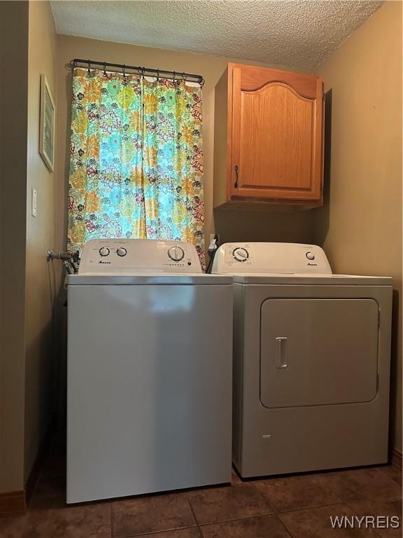 4710 Boncrest Dr E, Clarence, NY 14221 - laundry room featuring washing machine and dryer, cabinet space, a textured ceiling, and dark tile patterned flooring