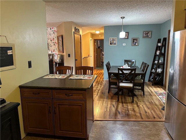 390 Bolivar Dr, Foster-Town, PA 16701 - kitchen with freestanding refrigerator, dark countertops, a textured ceiling, hanging light fixtures, and wood finished floors