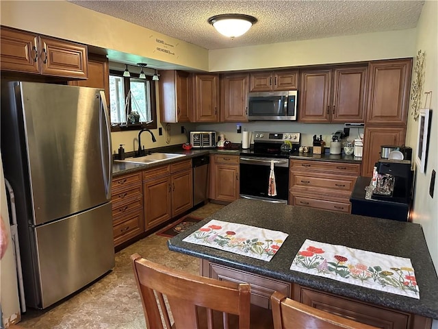 390 Bolivar Dr, Foster-Town, PA 16701 - kitchen featuring stainless steel appliances, a sink, a textured ceiling, dark countertops, and a kitchen breakfast bar