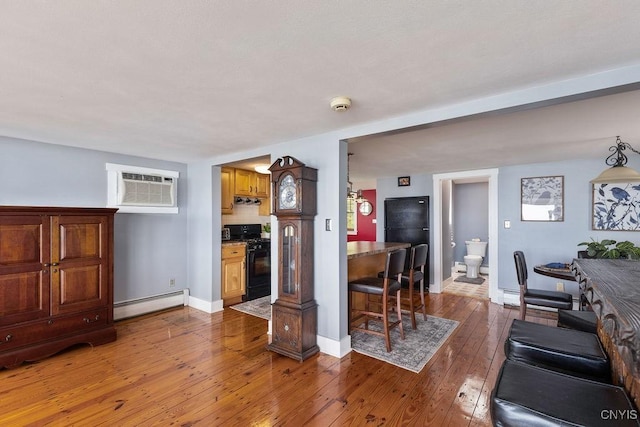 7649 Tuttle Rd, Cicero, NY 13030 - living room with baseboard heating, an AC wall unit, hardwood / wood-style floors, and baseboards