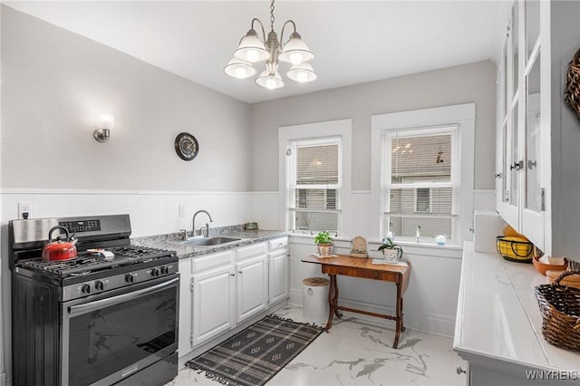 143 Lovering Ave, Buffalo, NY 14216 - kitchen featuring stainless steel range with gas cooktop, a sink, light marble finish flooring, a chandelier, and wainscoting