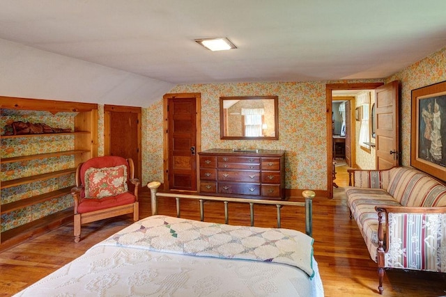 1031 Main St, Middletown, NY 12455 - bedroom with wallpapered walls, wood finished floors, vaulted ceiling, and baseboards