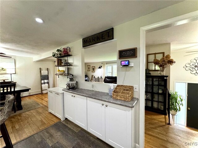 8521 Cazenovia Rd, Pompey, NY 13104 - kitchen with wood finished floors, white cabinets, baseboard heating, and recessed lighting