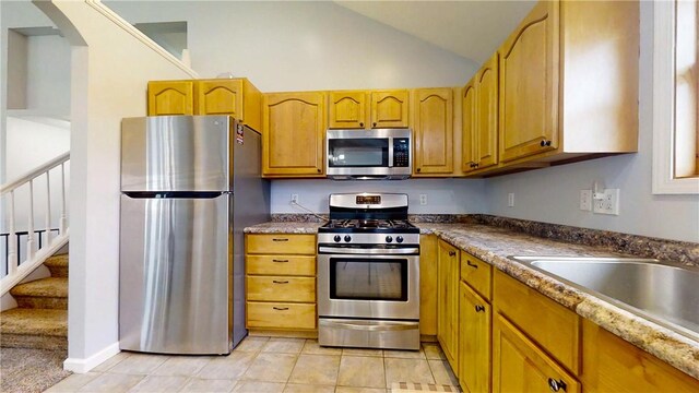 3638 Gorton Rd, Corning, NY 14830 - kitchen with appliances with stainless steel finishes, arched walkways, vaulted ceiling, light tile patterned floors, and brown cabinets