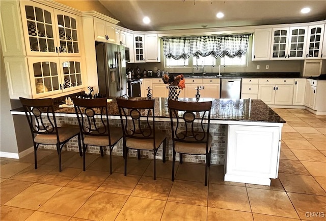 7290 State Route 80, Fabius, NY 13063 - kitchen with appliances with stainless steel finishes, a kitchen bar, glass insert cabinets, light tile patterned floors, and a sink