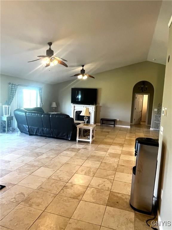 7290 State Route 80, Fabius, NY 13063 - living area featuring arched walkways, ceiling fan, lofted ceiling, a fireplace, and light tile patterned flooring