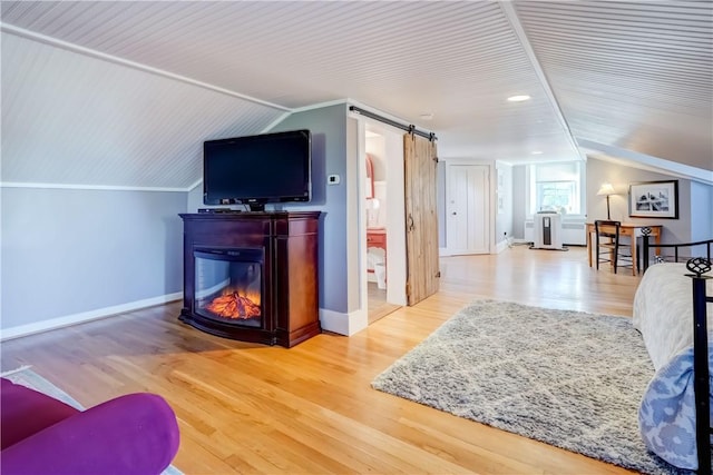 3402 W Lake Rd, Canandaigua Town, NY 14424 - living room with lofted ceiling, wood finished floors, baseboards, a barn door, and a glass covered fireplace