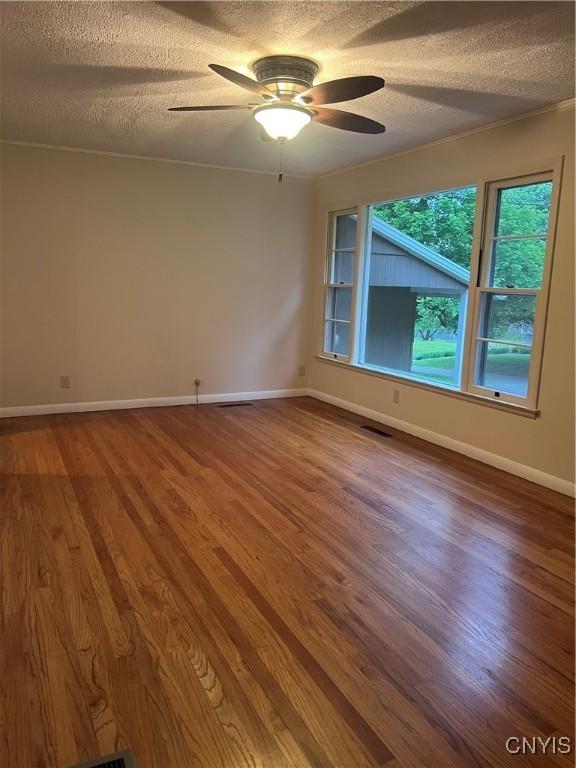 623 E Hamilton Ave N, Sherrill, NY 13461 - spare room featuring a textured ceiling, ceiling fan, wood finished floors, and baseboards