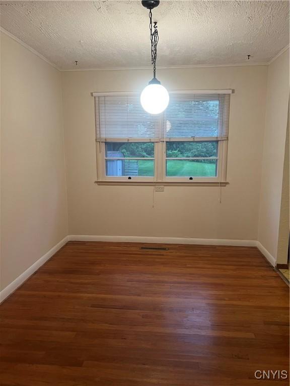 623 E Hamilton Ave N, Sherrill, NY 13461 - empty room featuring wood finished floors, a textured ceiling, ornamental molding, and baseboards