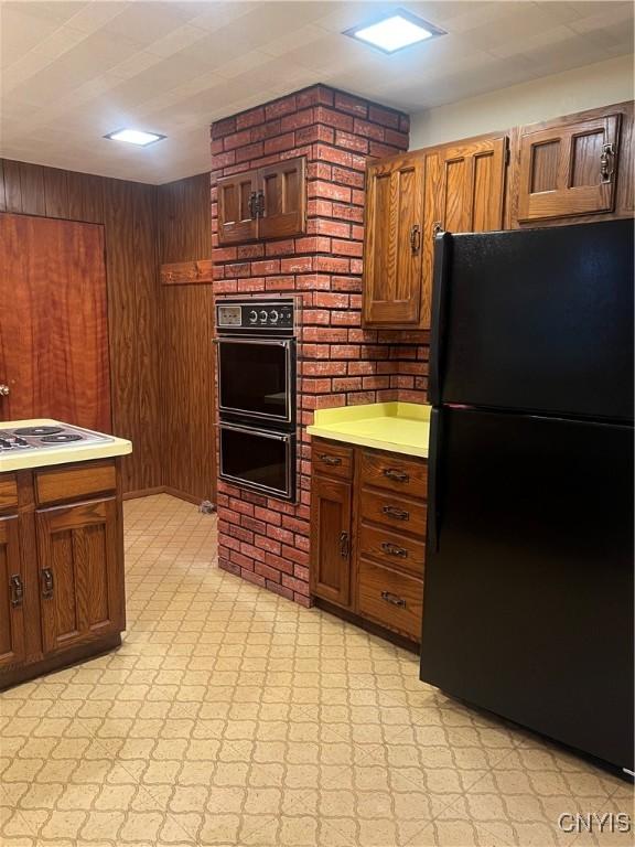 623 E Hamilton Ave N, Sherrill, NY 13461 - kitchen with black appliances, light countertops, wood walls, and brown cabinets