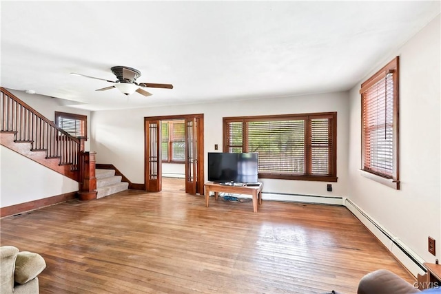 5549 State Route 104th Trl, Scriba, NY 13126 - unfurnished living room featuring stairway, wood finished floors, a baseboard heating unit, and a ceiling fan