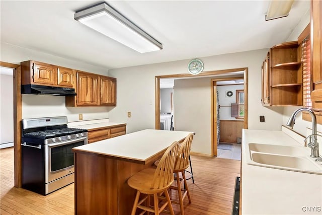 5549 State Route 104th Trl, Scriba, NY 13126 - kitchen featuring stainless steel gas range, a sink, under cabinet range hood, light wood-style floors, and washer and clothes dryer