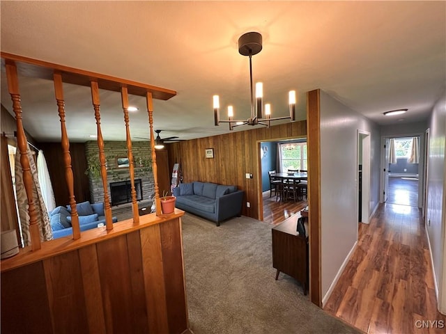 5030 Lincklaen Rd, Cuyler, NY 13158 - living area featuring a fireplace, a ceiling fan, a chandelier, healthy amount of natural light, and wooden walls