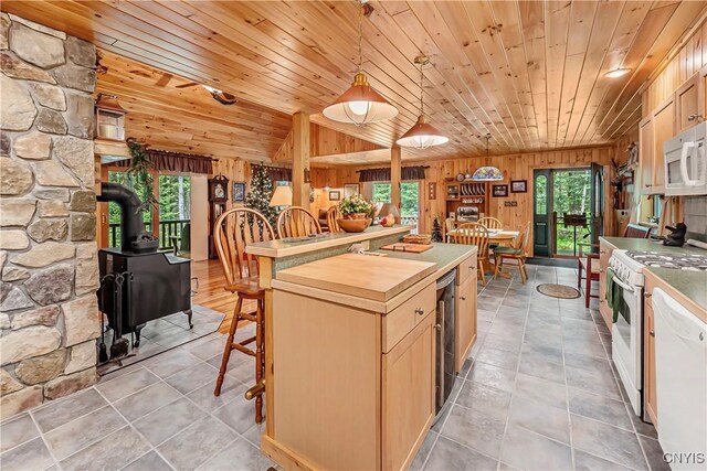 12103 Kincaid Rd, Forestport, NY 13338 - kitchen featuring white appliances, a wood stove, healthy amount of natural light, wood ceiling, and light tile patterned floors