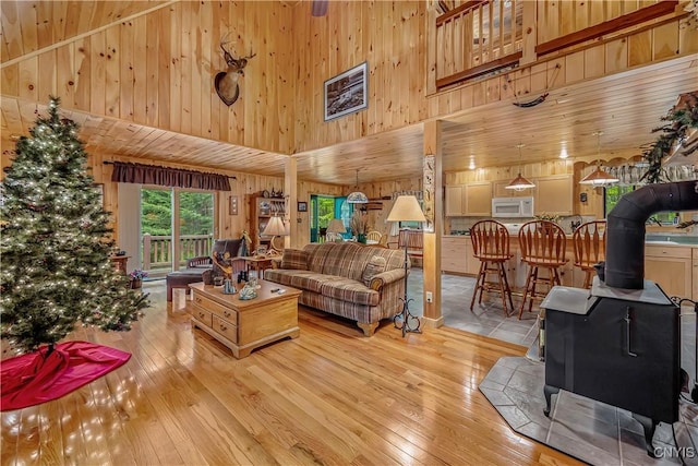 12103 Kincaid Rd, Forestport, NY 13338 - living area with a wood stove, wooden walls, a towering ceiling, and hardwood / wood-style floors