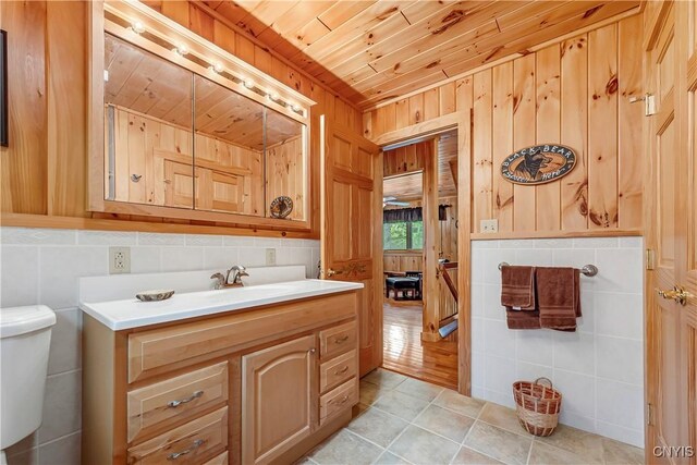 12103 Kincaid Rd, Forestport, NY 13338 - bathroom with vanity, toilet, wooden ceiling, tile walls, and wood walls