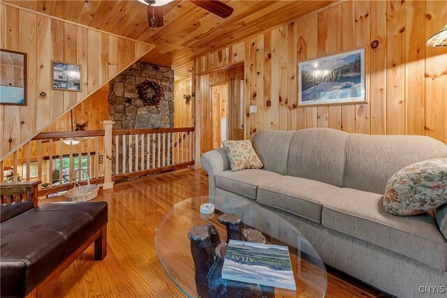 12103 Kincaid Rd, Forestport, NY 13338 - living room featuring wood walls, a ceiling fan, wooden ceiling, wood finished floors, and a stone fireplace