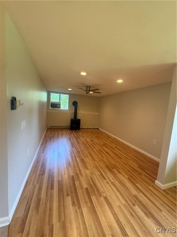 137 Watertree Dr, Dewitt, NY 13057 - unfurnished living room with a wood stove, light wood-style flooring, a baseboard radiator, baseboards, and recessed lighting