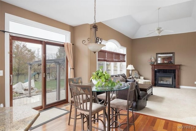 82 Arcadian Dr, Amherst, NY 14228 - dining area with healthy amount of natural light, a tiled fireplace, light wood-style flooring, ceiling fan, and lofted ceiling
