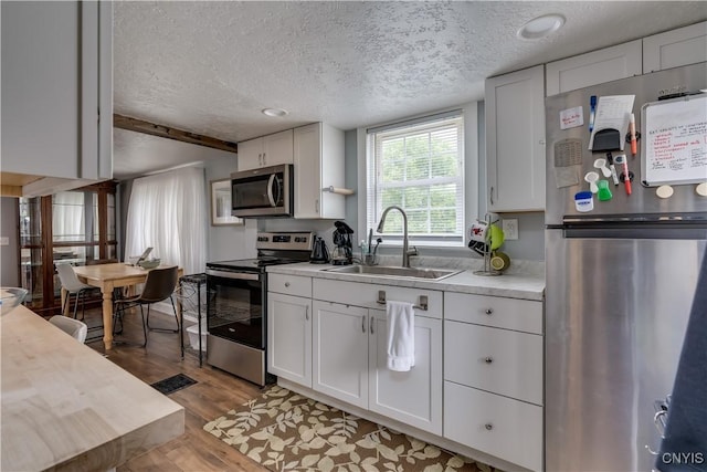 29580/584 Maple St Unit 584, Le Ray, NY 13612 - kitchen featuring stainless steel appliances, a sink, a textured ceiling, light countertops, and white cabinets