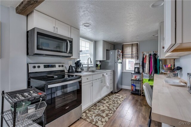 29580/584 Maple St Unit 584, Le Ray, NY 13612 - kitchen featuring appliances with stainless steel finishes, a sink, light countertops, wood finished floors, and white cabinetry