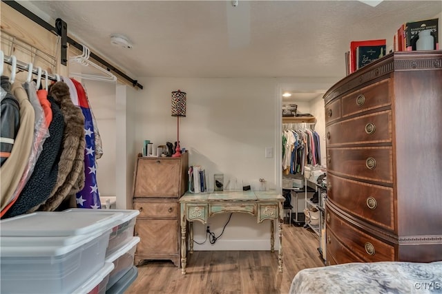 29580/584 Maple St Unit 584, Le Ray, NY 13612 - bedroom featuring a barn door, wood finished floors, a walk in closet, and a closet
