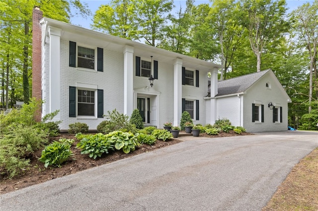 22 Whitecliff Dr, Pittsford, NY 14534 - neoclassical home featuring brick siding, a chimney, and asphalt driveway