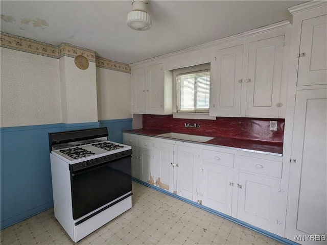 117 N 8th St, Olean-City, NY 14760 - kitchen featuring gas stove, a sink, light floors, white cabinets, and wallpapered walls