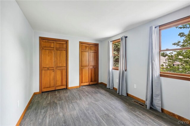 8005 Fir Dr, Clay, NY 13041 - unfurnished bedroom with wood finished floors, baseboards, and multiple closets