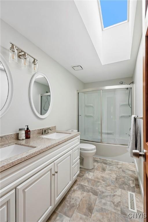 8005 Fir Dr, Clay, NY 13041 - full bathroom featuring a skylight, double vanity, toilet, and bath / shower combo with glass door