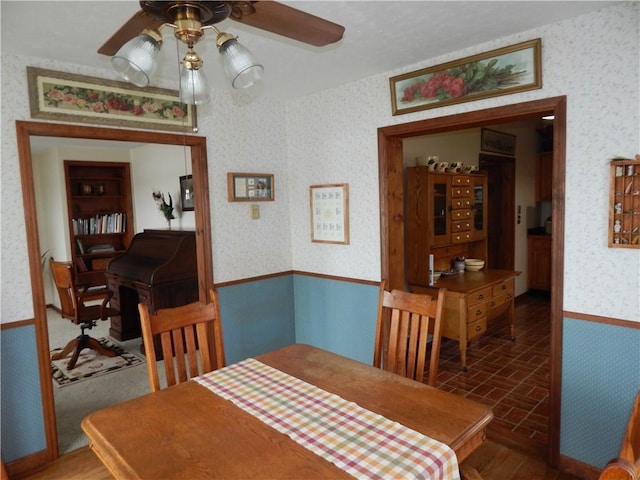 6731 Lake Salubria Dr, Bath, NY 14810 - dining area featuring wallpapered walls, ceiling fan, brick patterned floors, and a wainscoted wall