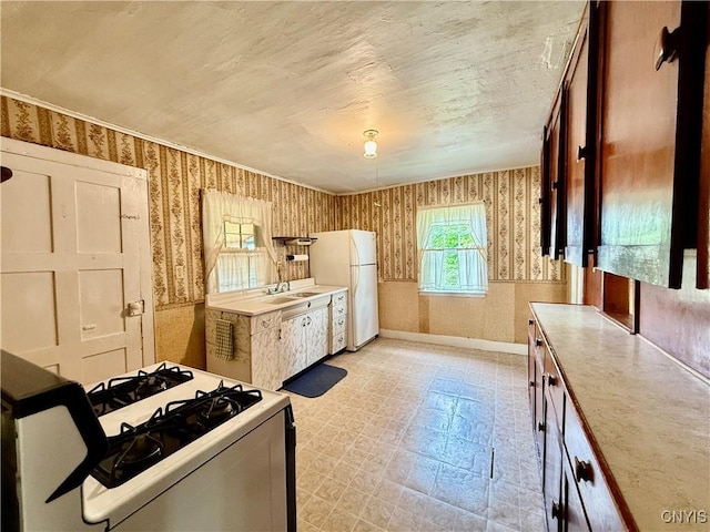 4151 State Route 20, Nelson, NY 13408 - kitchen featuring wallpapered walls, freestanding refrigerator, gas range oven, a sink, and light floors