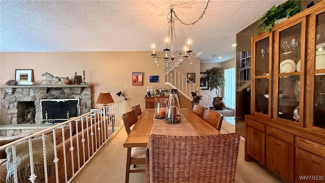 3134 E River Rd, Grand Island, NY 14072 - dining area featuring a textured ceiling, a chandelier, stairs, a fireplace, and light colored carpet