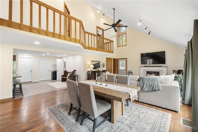 147 Crooked Lake Rd, Tully, NY 13159 - dining area with a lit fireplace, high vaulted ceiling, a ceiling fan, hardwood / wood-style flooring, and rail lighting