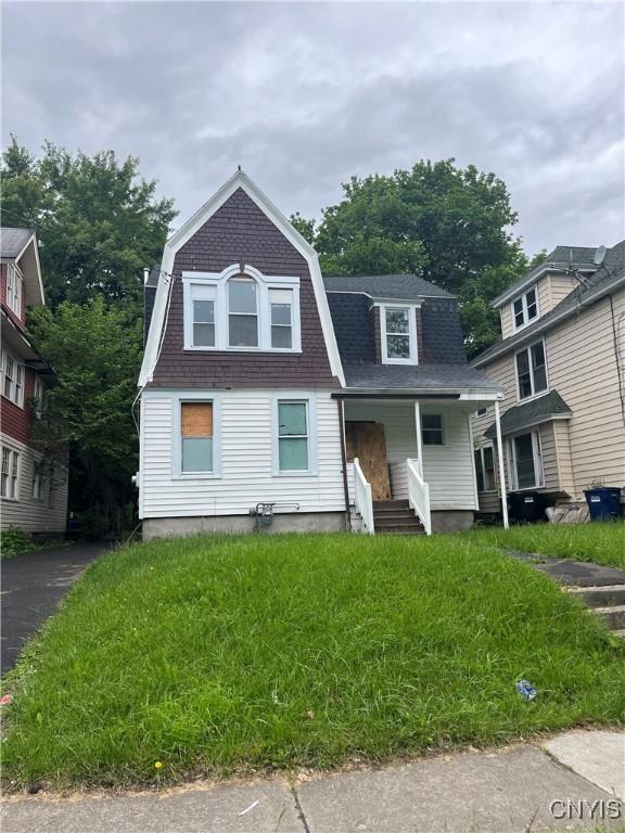 2608 Midland Ave, Syracuse, NY 13205 - colonial inspired home featuring a gambrel roof, a shingled roof, and a porch