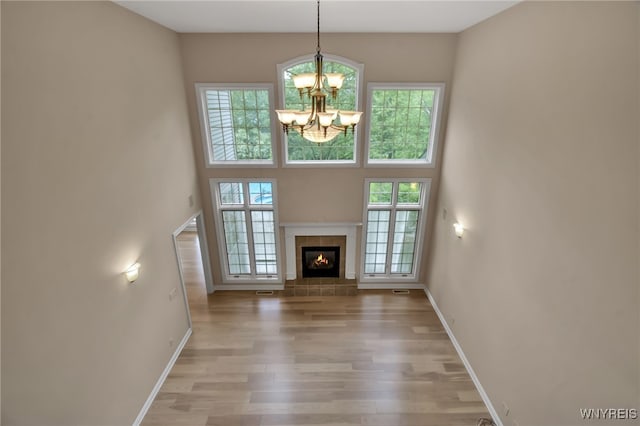 25 Davinci Ct, Amherst, NY 14221 - unfurnished living room featuring a chandelier, baseboards, light wood finished floors, and a tiled fireplace