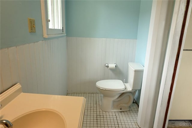 801 Ballantyne Rd, Syracuse, NY 13207 - bathroom with toilet, wainscoting, a sink, tile patterned floors, and wood walls
