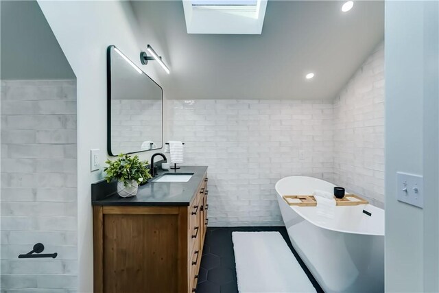 100 Eastland Ave, Brighton, NY 14618 - full bath featuring double vanity, a freestanding bath, a skylight, tile patterned floors, and tile walls