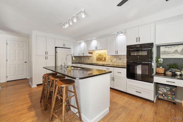 4962 Tall Oaks Dr, Manlius, NY 13066 - kitchen featuring freestanding refrigerator, cooktop, dark countertops, white cabinets, and light wood finished floors