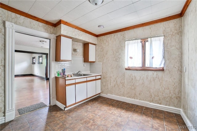 421 E Utica St, Buffalo, NY 14208 - kitchen featuring crown molding, a sink, light countertops, white cabinetry, and baseboards