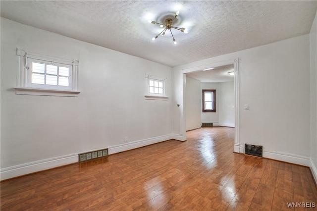 421 E Utica St, Buffalo, NY 14208 - spare room featuring hardwood / wood-style floors, a textured ceiling, baseboards, and a chandelier