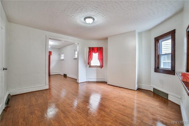 421 E Utica St, Buffalo, NY 14208 - unfurnished room with healthy amount of natural light, hardwood / wood-style flooring, a textured ceiling, and baseboards