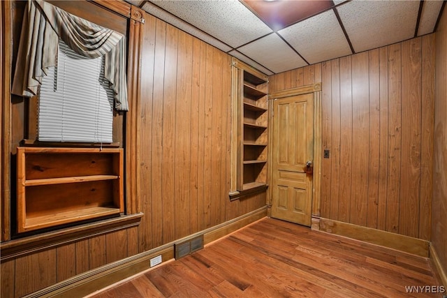 421 E Utica St, Buffalo, NY 14208 - spare room with wood walls, wood finished floors, baseboards, and a paneled ceiling