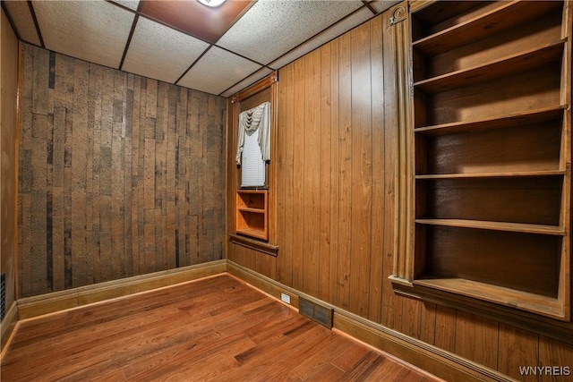 421 E Utica St, Buffalo, NY 14208 - spare room featuring wooden walls, wood finished floors, baseboards, and a drop ceiling