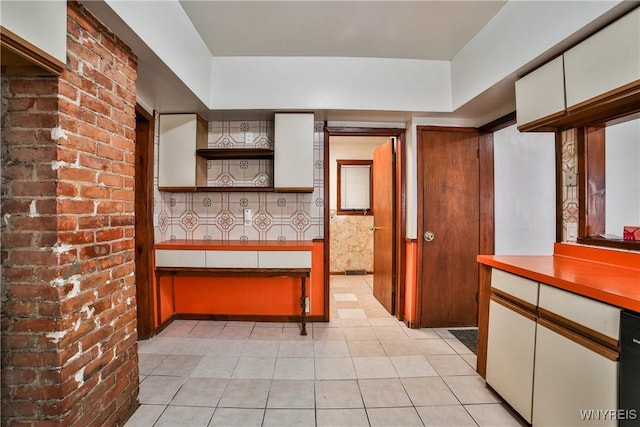 421 E Utica St, Buffalo, NY 14208 - kitchen with white cabinetry, light countertops, light tile patterned floors, open shelves, and brick wall